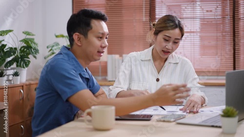Two Asian Colleagues Collaborating and Discussing Project Data on Laptop Screen