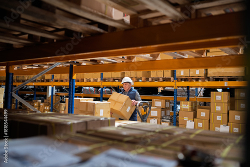 Fotografía Senior male warehouse worker unloading boxes from a pallet truck.