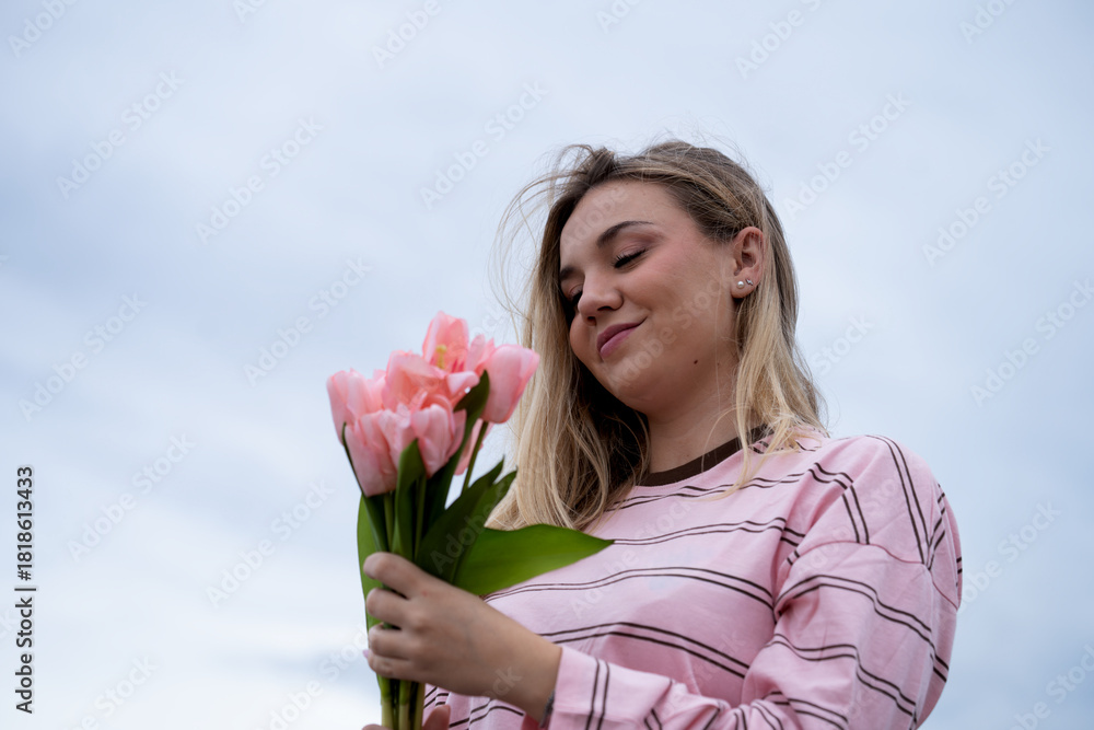 Fototapeta premium Young woman smiling holding pink tulip bouquet