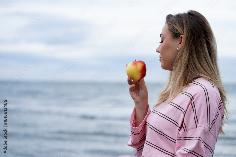 Φωτογραφία Woman holding apple contemplating healthy lifestyle by sea