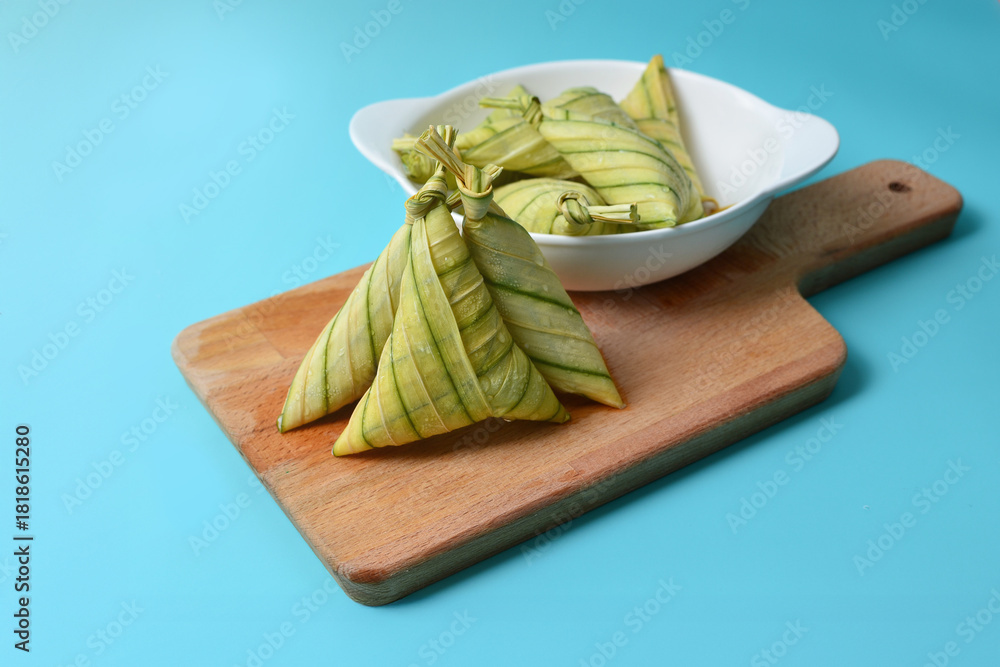 Φωτογραφία Freshly wrapped ketupat palas arranged on a wooden board, highlighting their neat folds and traditional charm against a clean, bright background