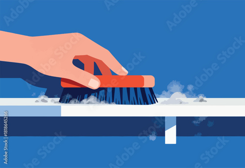 A hand brushes a surface with an orange brush, creating clouds of debris on blue backdrop
