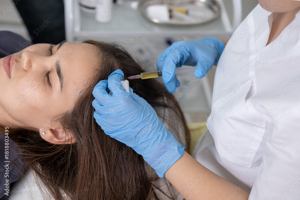 Fototapeta premium Doctor is doing a plasma therapy injecting head for healthy hair growth. Professional medical worker uses small syringe needle for injections plasma therapy close-up