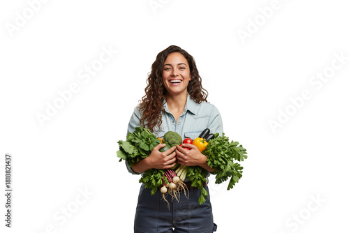 A beaming young woman with curly hair holds a large armful of fresh, colorful vegetables