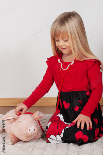 little girl playing doctor with her toy pig at home