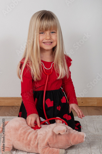 little girl playing doctor with her toy pig at home