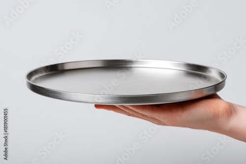 Close-up of a waiter's hand holding an empty metal tray on a white background. Restaurant employee concept.