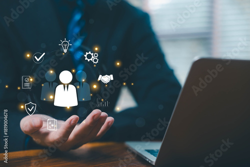 Businessman holding digital HR icons representing people management, employee relationship, teamwork, recruitment strategy, and modern human resources solutions in a digital business environment.
