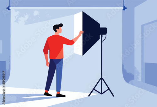 A figure in red adjusts a photography studio light, against a backdrop in a blue toned studio space