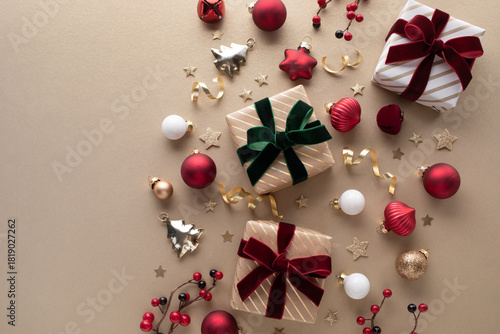 Elegant golden gift or present boxes with velvet red and green ribbon with festive decoration on light beige background for Christmas or New Year greeting card