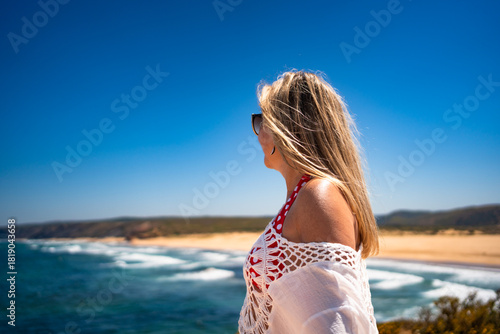 Portrait of beautiful middle-aged woman standing against ocean and sandy beach background