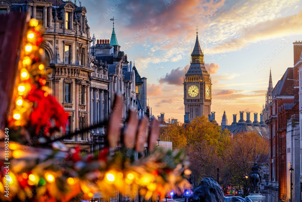 Fototapeta premium Winter sunset view of the Big Ben clock tower in London, England, with blurred fairy lights from the Trafalgar Square Christmas market in front