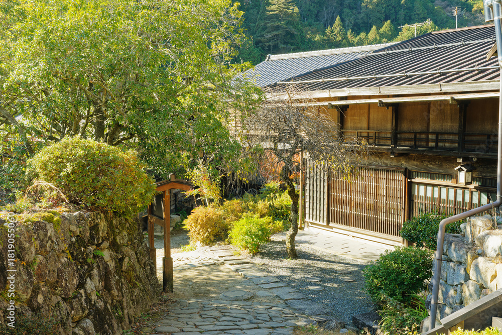 Obraz premium Stone path, garden shrubs and traditional wooden house in Tsumago-juku, Nagano, Japan