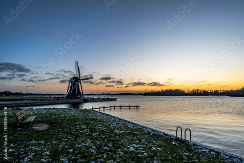 Winter landscape with Dutch windmill along lake Paterswoldsemeer, Groningen, The Netherlands