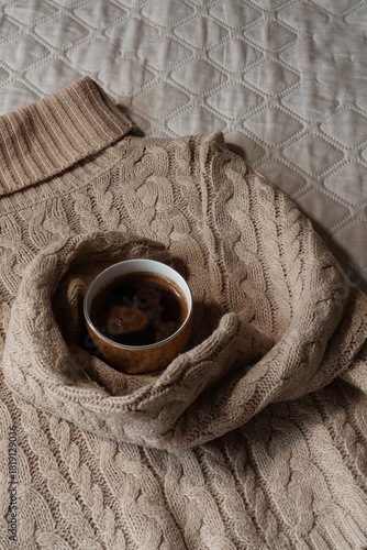 Espresso coffee in a mug on a gray background. Coffee in a cozy beige sweater. Concept of a morning drink in an autumn mood.