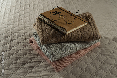 Stack of warm sweaters, book and glasses