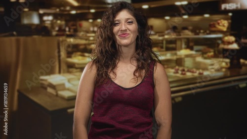 Wallpaper Mural Woman smiling at camera in a kitchen studio, visible shoulders and hands resting on a food display counter with pastries and plates; joy warm hospitality. Torontodigital.ca