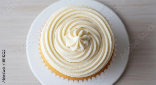 Top down view of a delicious vanilla cupcake with a perfect swirl of creamy white frosting, a delightful sweet treat