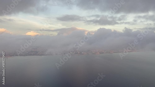Aerial view flying trough clouds with a view on Barcelona at sunrise