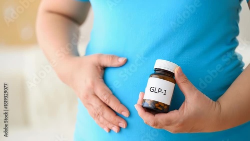 GLP-1 bottle held by overweight person wearing blue shirt, focus on abdomen, healthcare concept, weight management, medical information, pharmaceutical setting