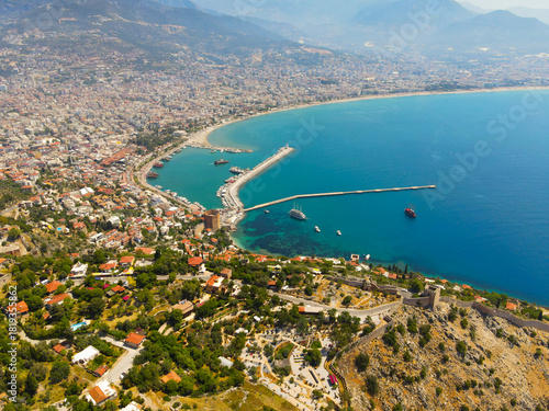 Fototapeta Naklejka Na Ścianę i Meble -  Wide aerial panoramic shot showing the coastline, Alanya city, the harbor pier, and the Mediterranean Sea