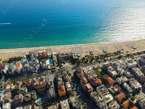 Fototapeta Naklejka Na Ścianę i Meble -  Top-down aerial view looking straight down on densely packed city blocks and apartment buildings adjacent to the sandy beach and clear Mediterranean Sea