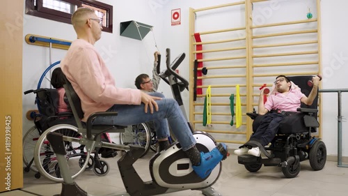 People with disabilities doing physiotherapy exercises in a specialized clinic. Man using a stationary bike and another lifting weights