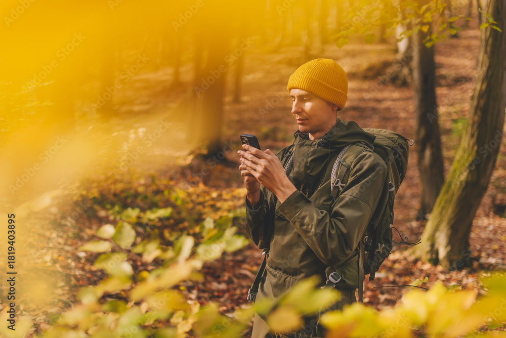 Fototapeta premium Man Hiker Using Smartphone for Navigation in Forest