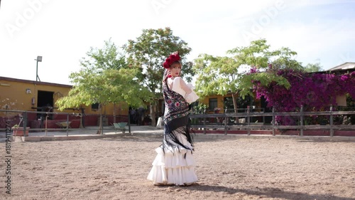 Beautiful woman in traditional white dress and black shawl dancing flamenco in a sandy courtyard. Her passionate performance embodies spanish culture