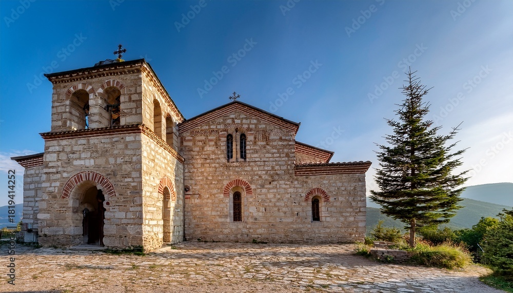 Fototapeta premium The Weathered Stone Facade Of The Saint Nikola Church In Dryanovo Bulgaria With Its Distinctive Arched Windows And A Small Pine Tree In The Foreground Evokes A Sense Of Timeless Beauty