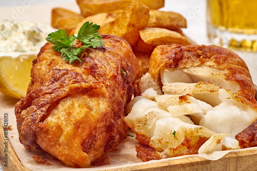 Tender fish and chips beneath crispy golden coating, fried fish with aromatic batter and flaky texture showcased