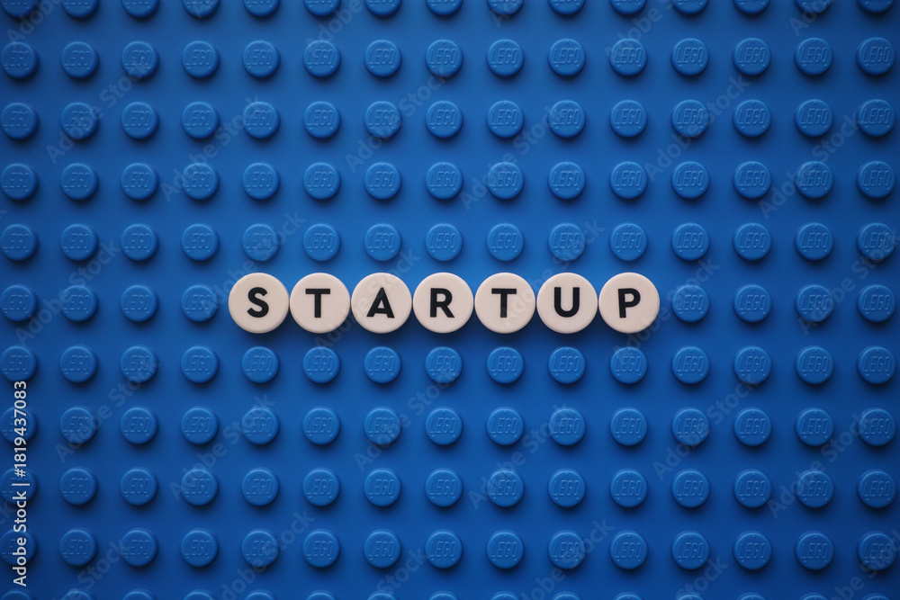 Naklejka premium Tambov, Russian Federation - November 24, 2025 The word Startup on a blue Lego baseplate. The scene is made out of Lego dots.