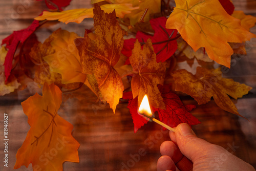 Setting fire to autumn leaves with a match.