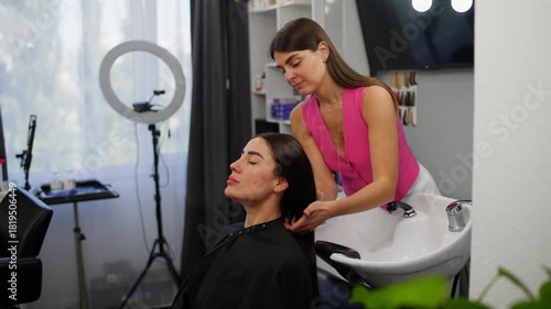 The hairdresser carefully helps the client lower her head into the sink. High quality 4k footage