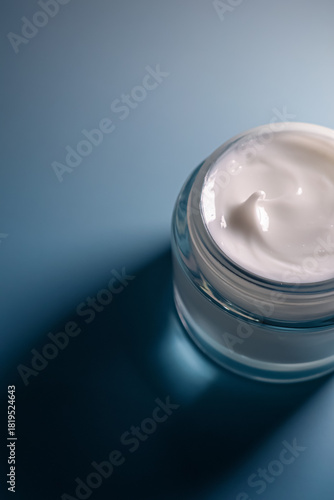 Creamy white moisturizer in an open glass jar. Concept of beauty, skincare, hygiene, and daily routine