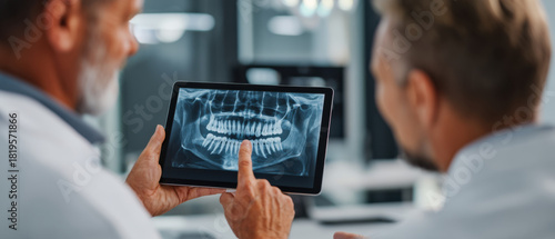 Two people looking at dental x-ray on tablet