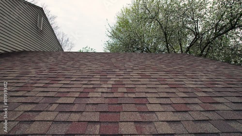 Drone shot and close up macro of rows and lines of roof shingles on older house in midwest Ohio dollying in towards angular shaped roofline on top of grey and warm home that needs new rooftop