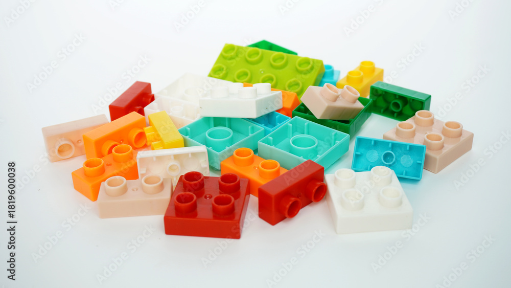 Obraz premium a pile of small plastic blocks or plastic blocks of various shapes, sizes, and colors that can be connected to each other and assembled into various shapes, isolated on a white background