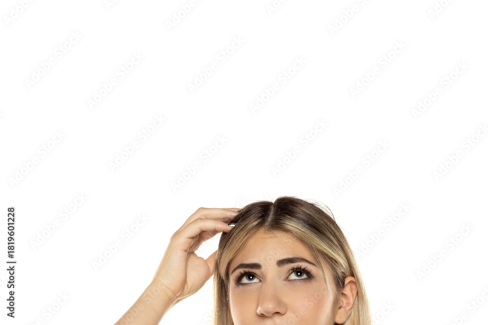 Fototapeta premium Half portrait Close-up of blonde woman scratching her head and looking up with curious expression, empty white background with copy space above head, studio shot