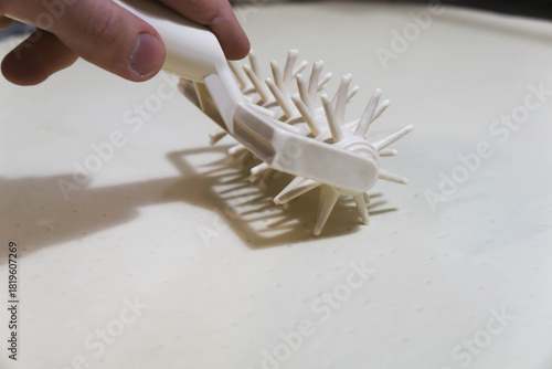 Canvas Print Close-up of a professional dough docker perforating pizza dough to prevent air bubbles during baking