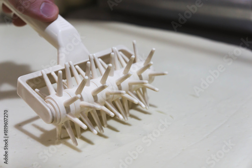 Fotografi Close-up of a professional dough docker perforating pizza dough to prevent air bubbles during baking