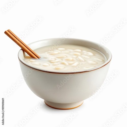 Sweet canjica or hominy pudding with white corn kernels and a cinnamon stick, isolated on white background
