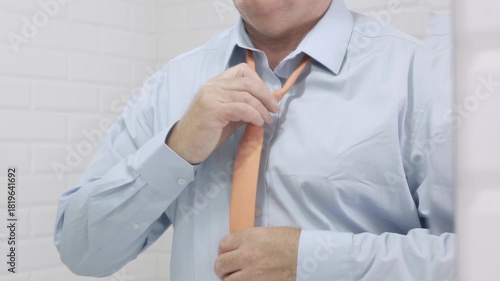 Blurred Shooting with a Borred Businessman in the Mirror Wearing a Blue Shirt and Untying a Tie from His Neck.
