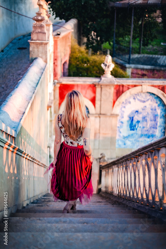 Woman walking down historic staircase at Estoi Palace during golden hour