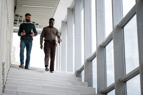 Business professional men walking downstairs in office building