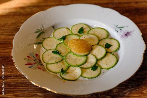 Zucchini carpaccio with pollock caviar and mint leaves on a vintage plate.