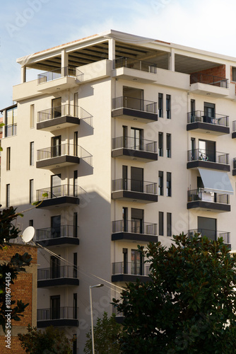 Vertical image of a minimalist modern building with greenery around it creates a clean urban feel. Suitable for real estate marketing, rental apartments, and property buyers relocating abroad.