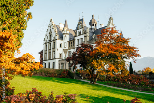 European castle surrounded by autumn foliage and bright green grass