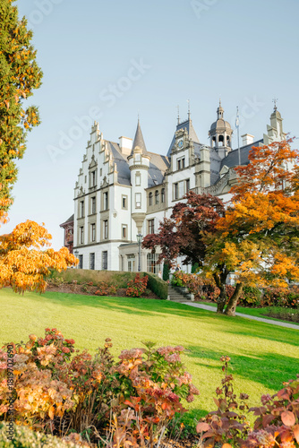 European castle surrounded by autumn foliage and bright green grass