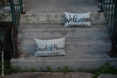 Welcome and Beach house throw pillows on cement staircase